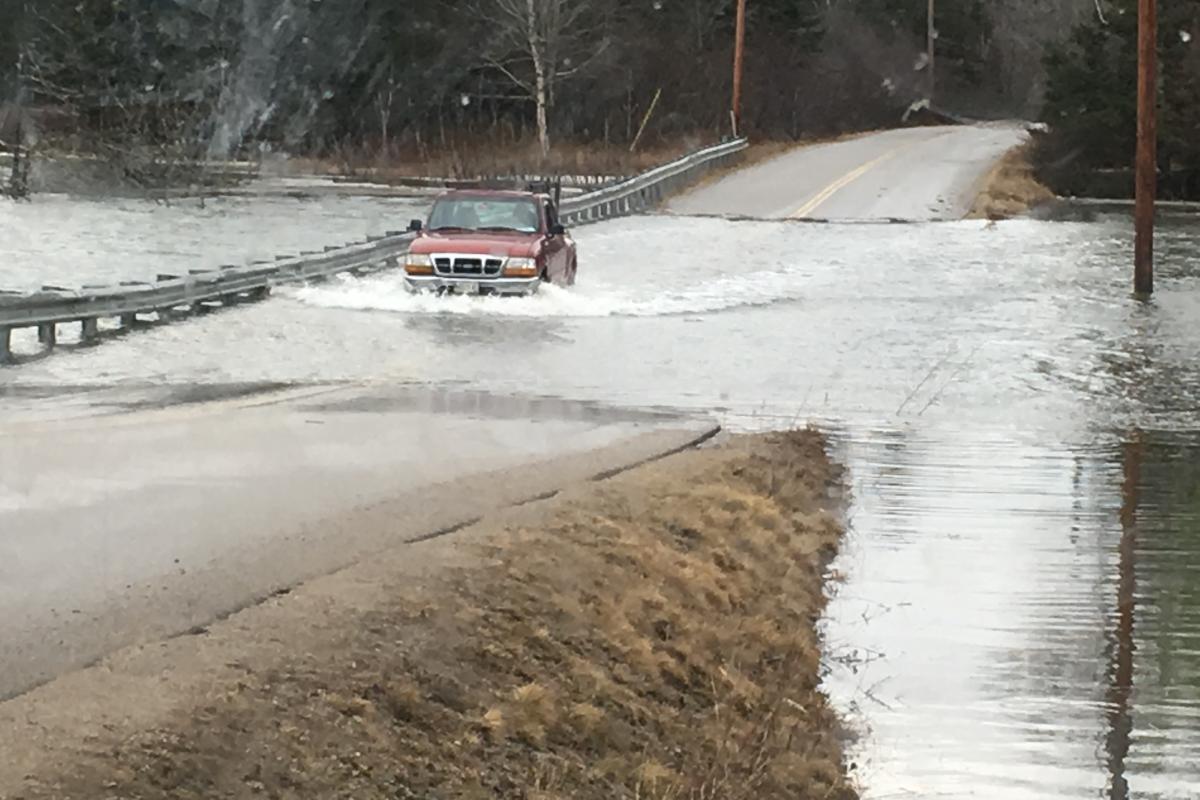 small red ford pickup driving through a flooded roadway